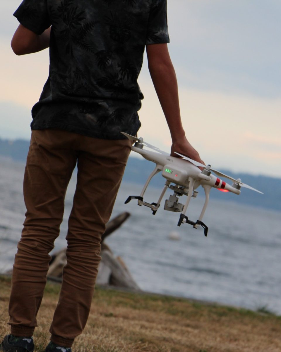 Noah at 12, holding his first drone, a white DJI Phantom, by the water